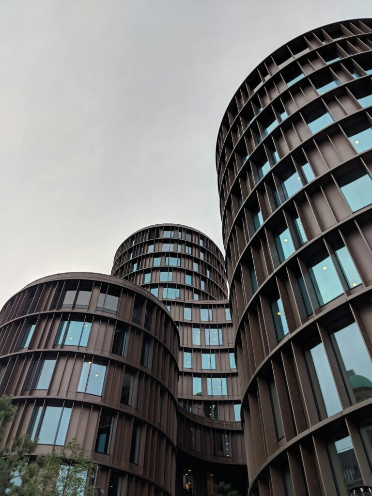 "A low-angle view of the circular Axel Towers in Copenhagen, symbolizing the structured 'Systems' of policy and finance.